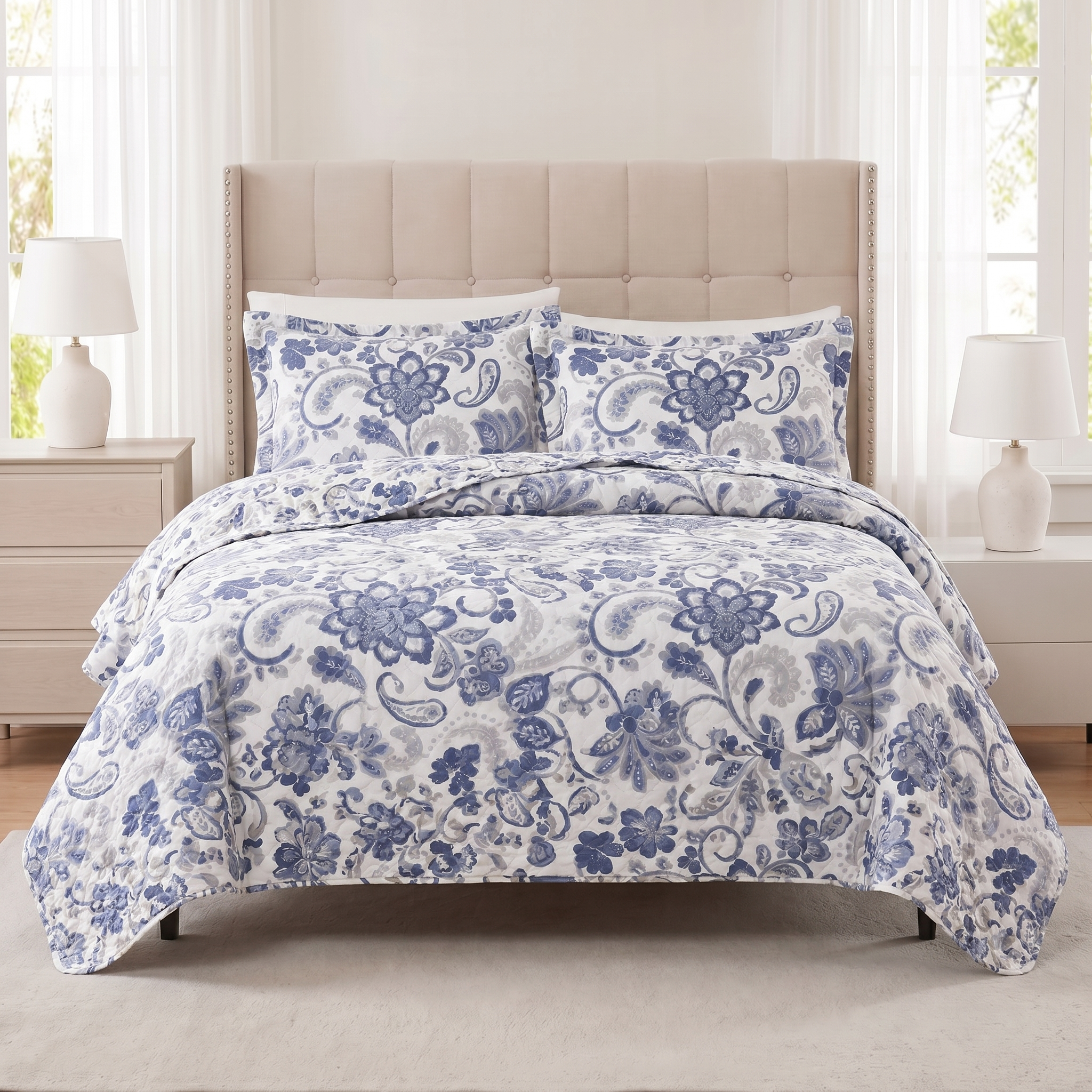 Blue floral bedding set on a bed in a bedroom with lamps and nightstands.