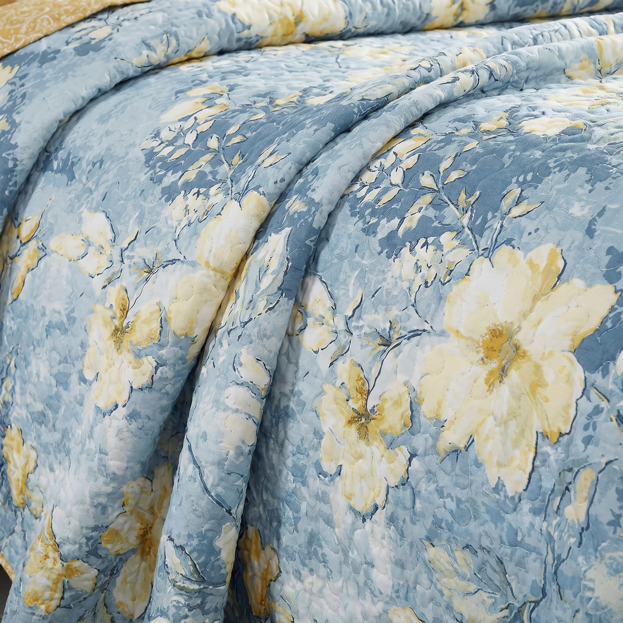 Floral patterned comforter with yellow flowers on a blue background