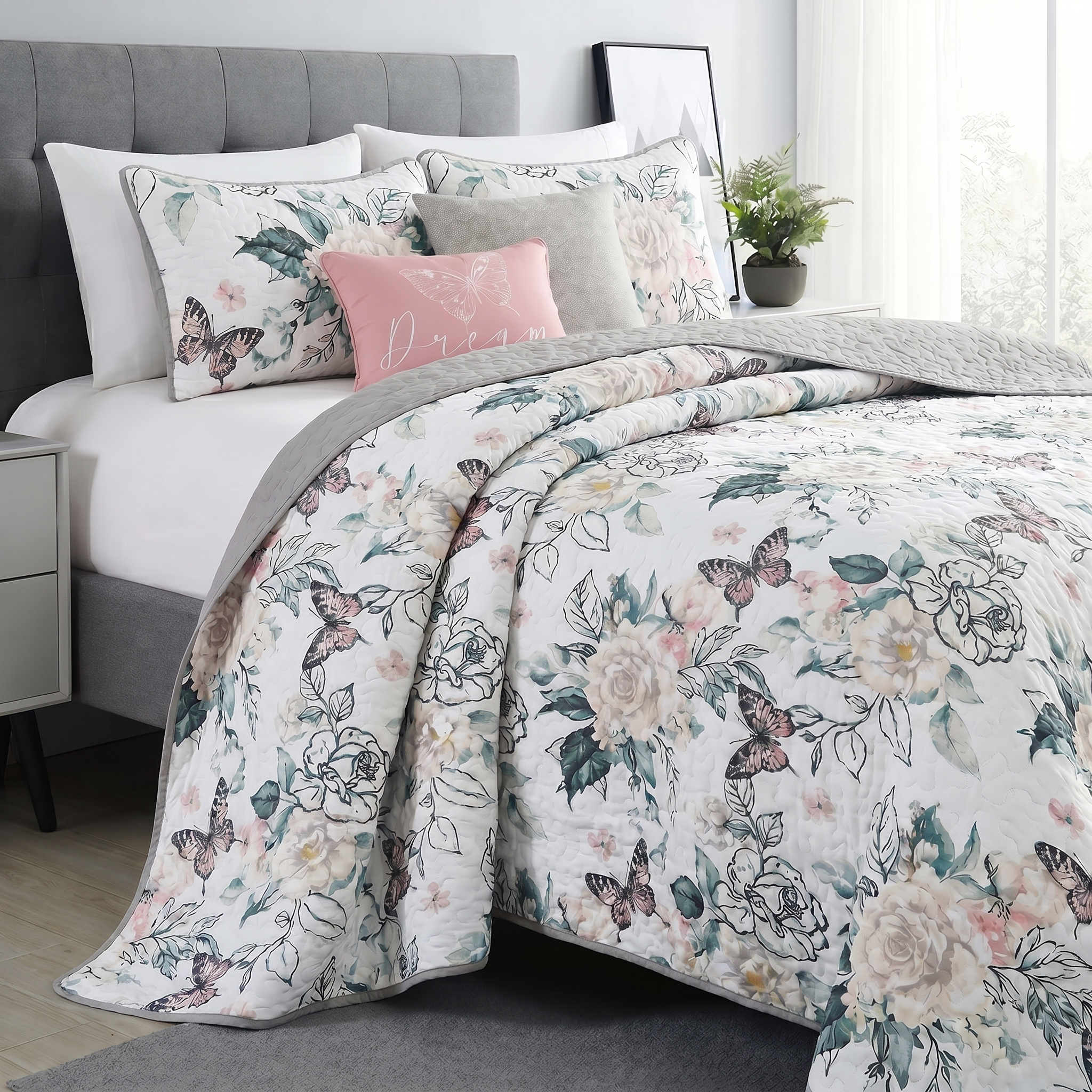 Floral and butterfly patterned bedding set on a bed with pillows.