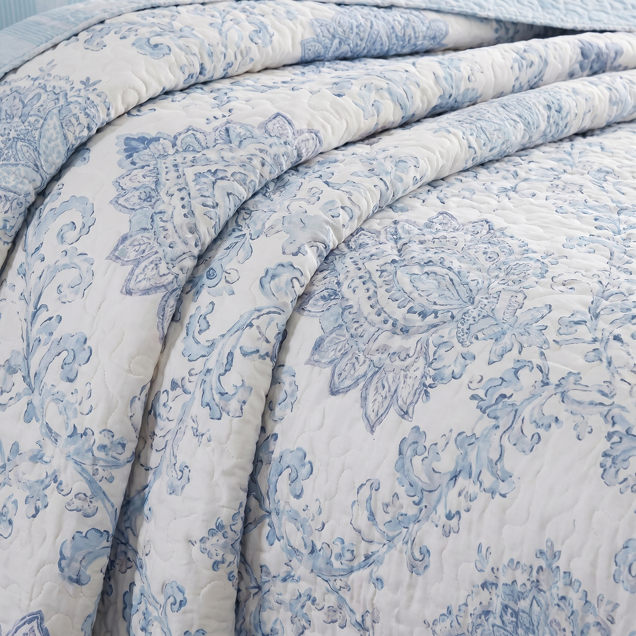 Blue and white floral patterned quilt on a bed